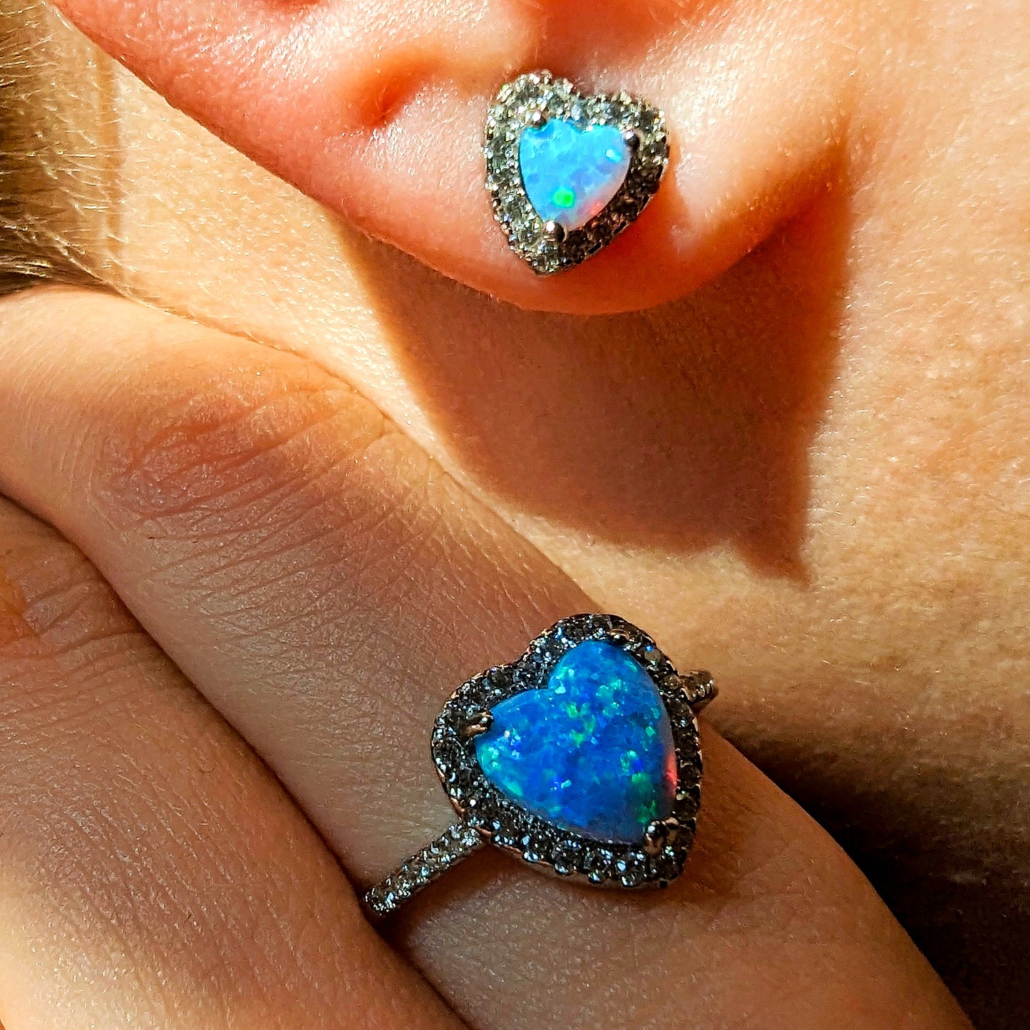 Elegant jewellery set featuring blue heart-shaped ring and earrings worn by model.