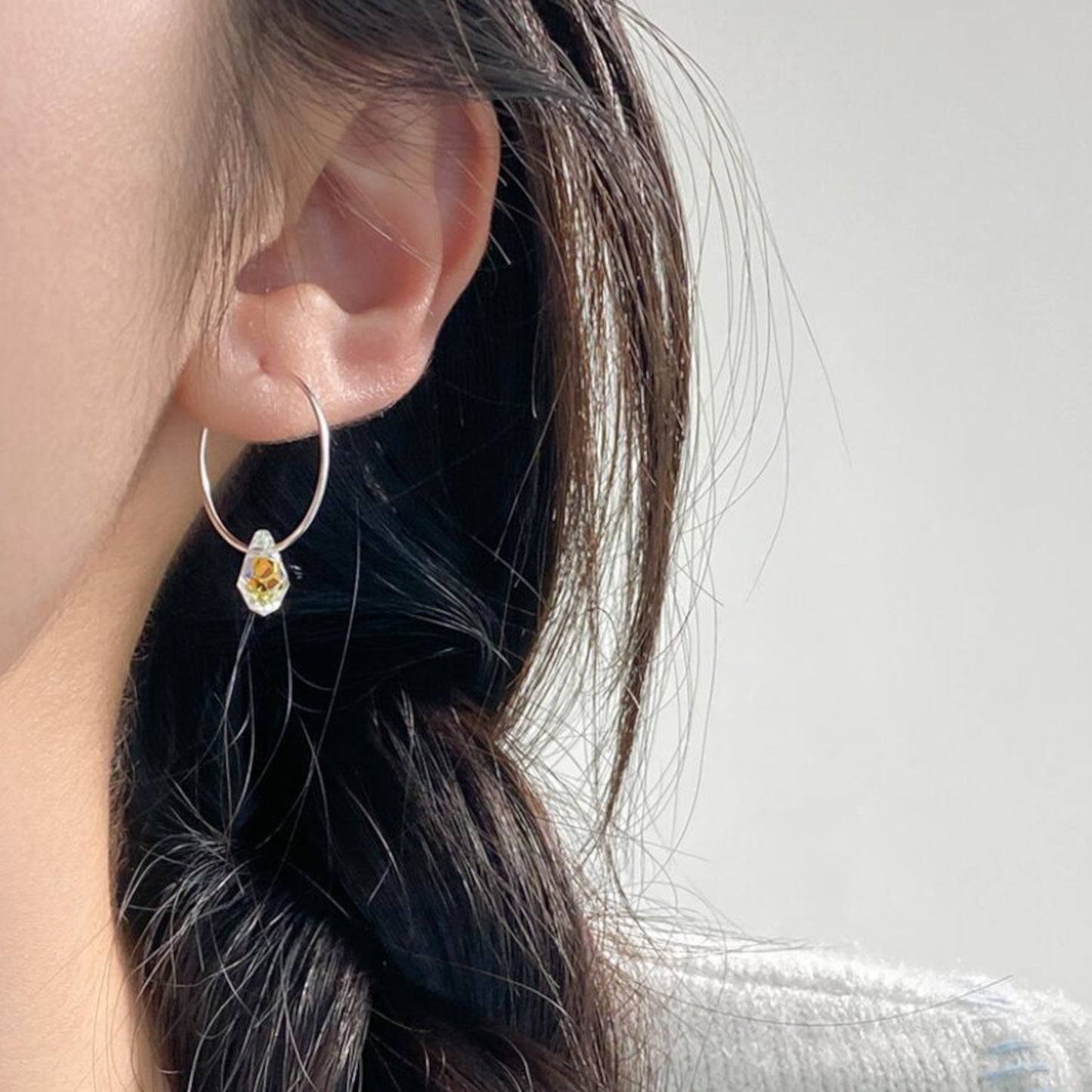 Dangling hoop earrings with synthetic crystal drops in sterling silver, shown worn.