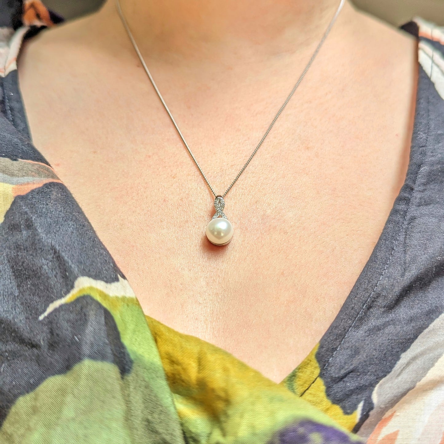 Model wears round pearl pendant on a silver chain.