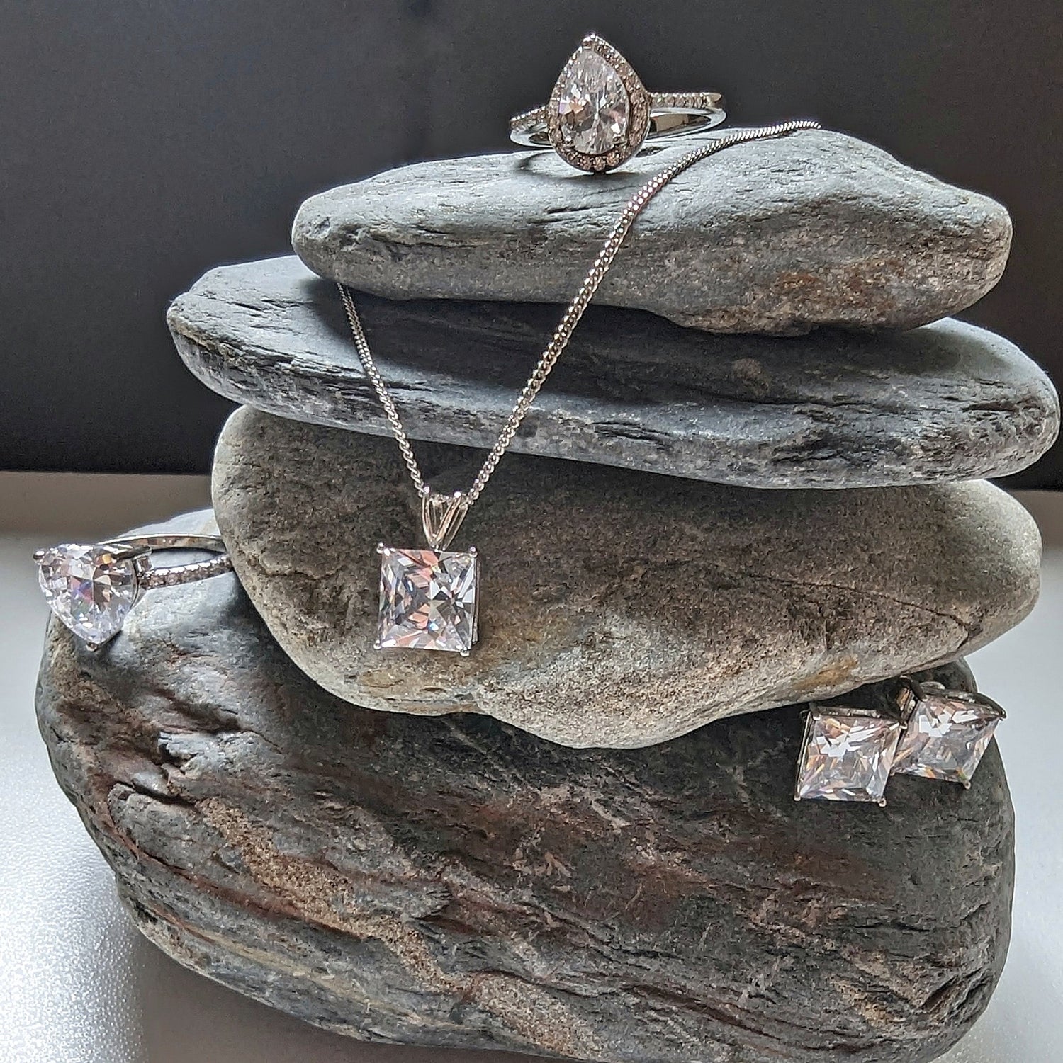 Ring, Necklace and earrings laid out on stones.