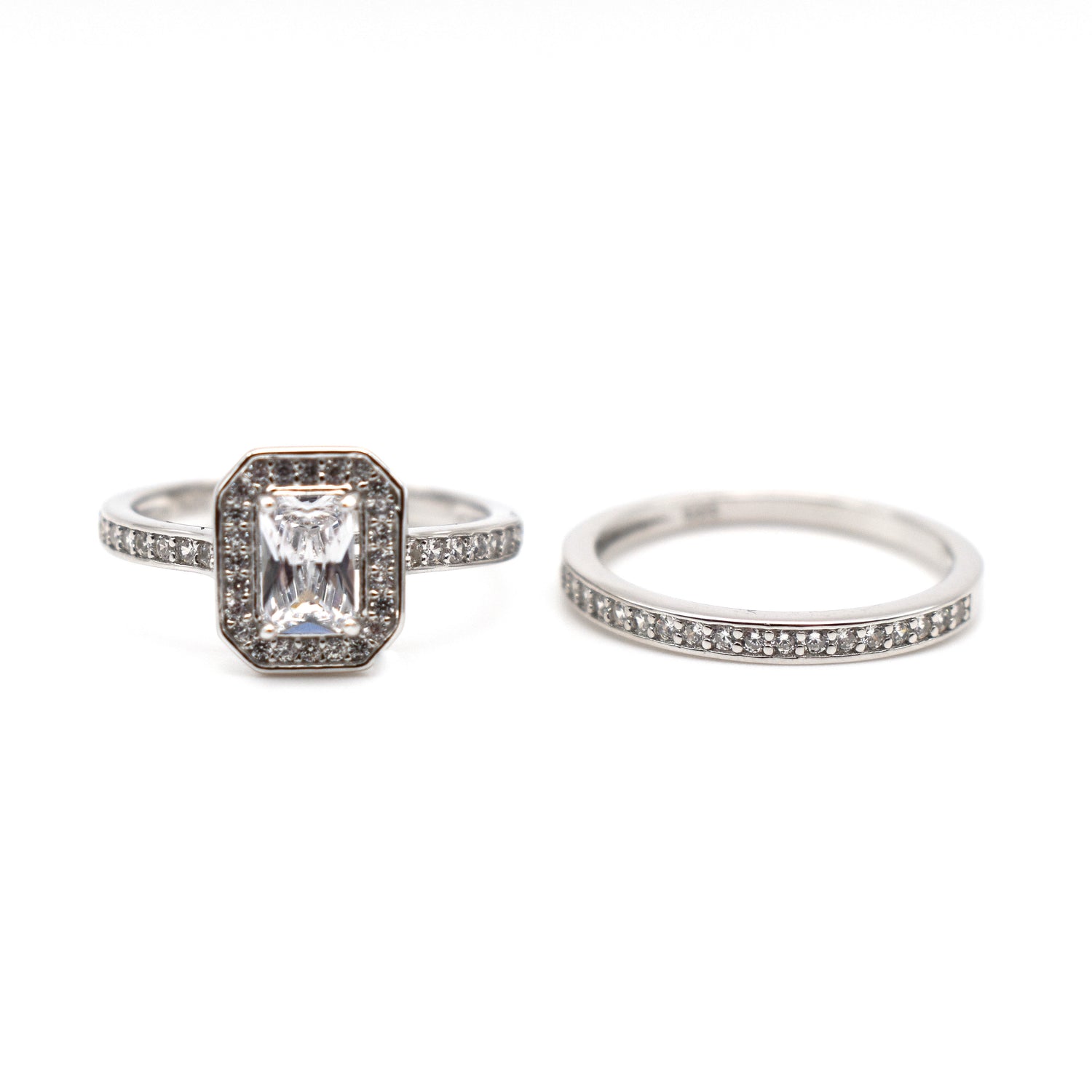 Two sterling silver and cubic zirconia encrusted rings, one features a emerald cut whilst the other is a silver band. 