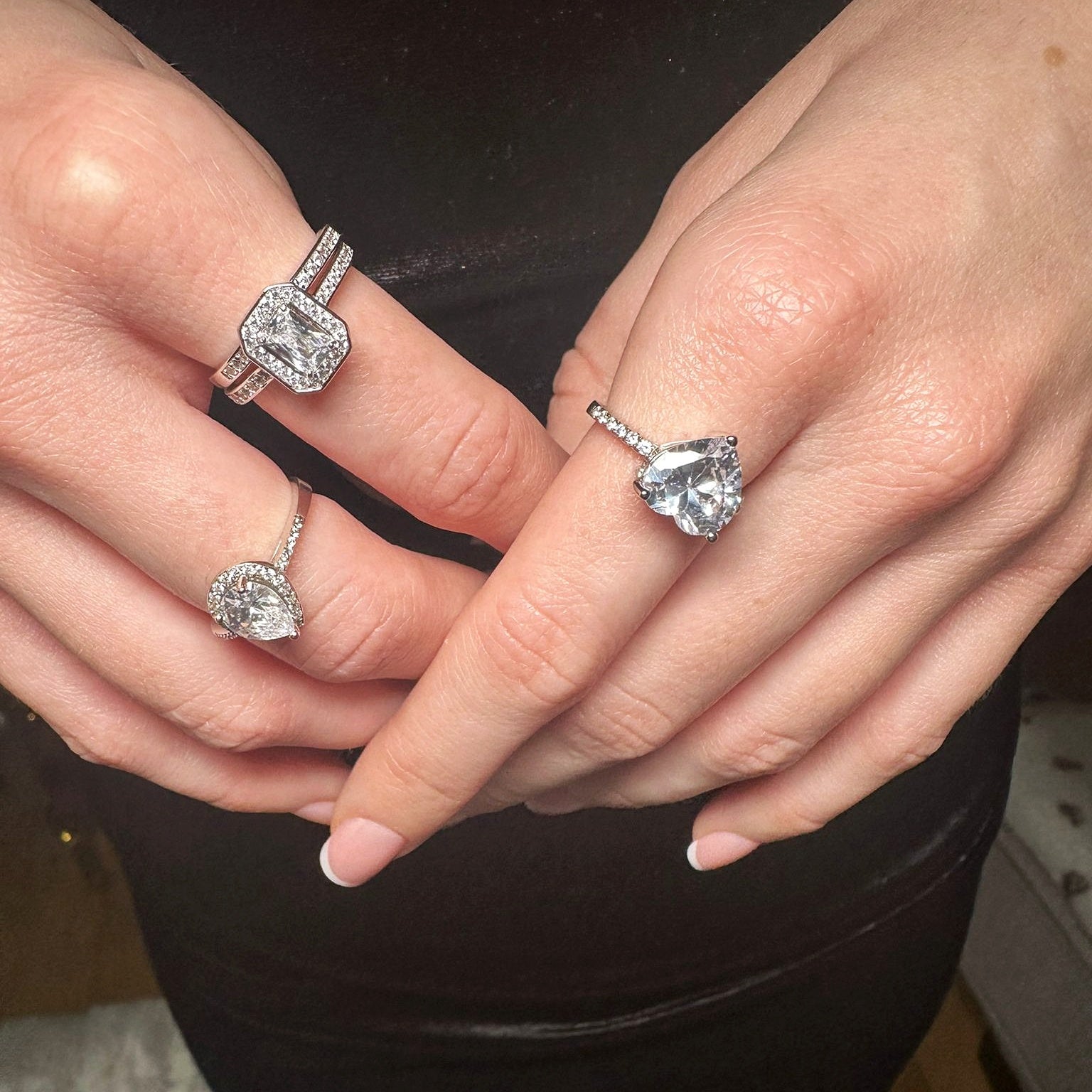 Three statement rings with heart, pear, and emerald-shaped stones worn on model's fingers.